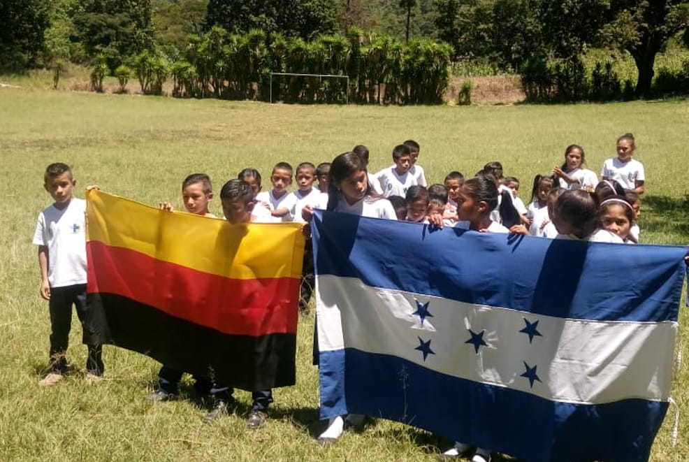 Patenbesuch Honduras ODECO/Limoncito: Kindergruppe auf Wiese mit Landesfahnen (Quelle: privat / Kindernothilfe)